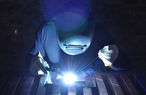 Person welding with sparks, blue overlay of color on the image
