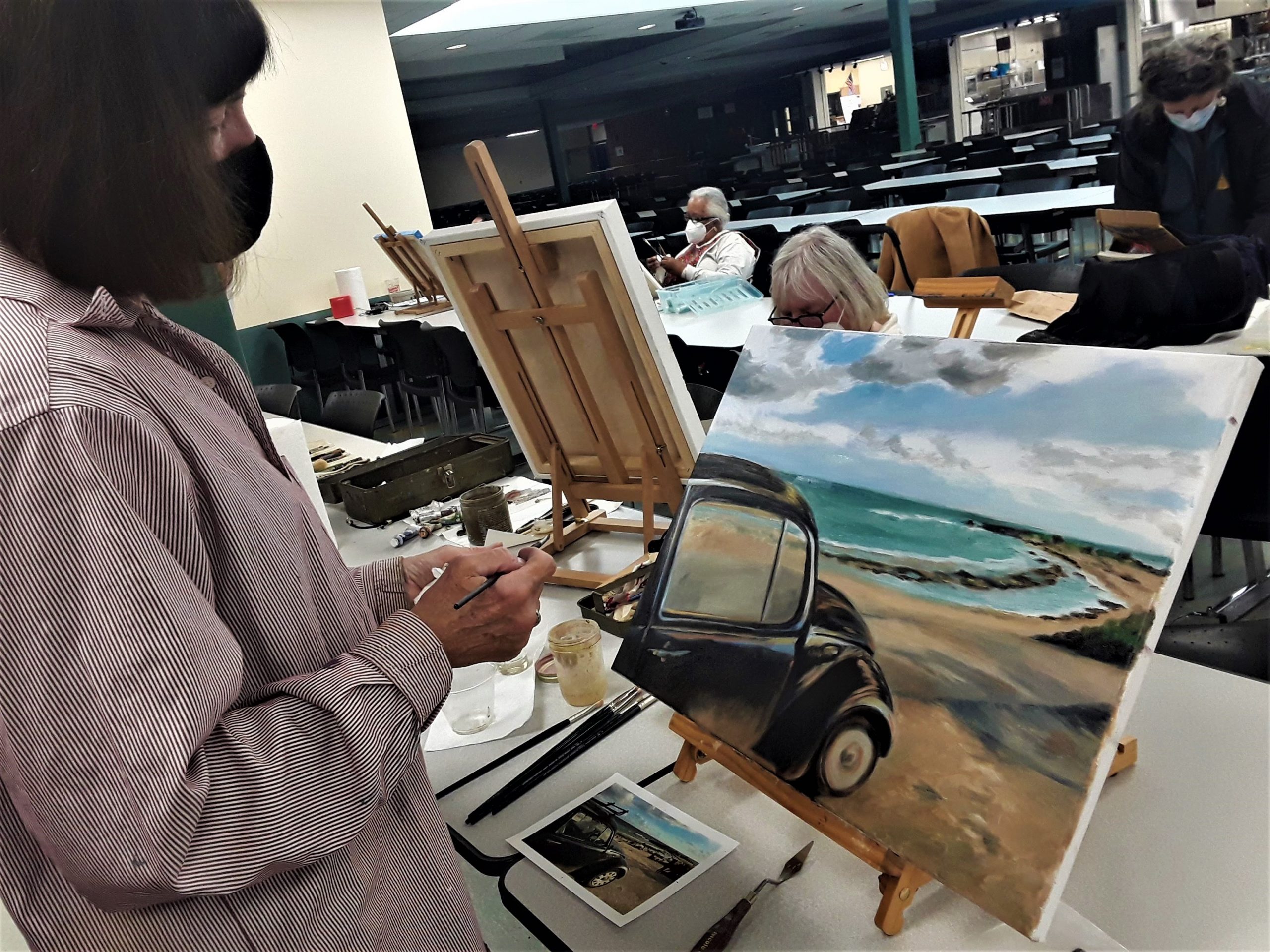 Students painting with on easels - front image student has a volkswagen buggy on the beach