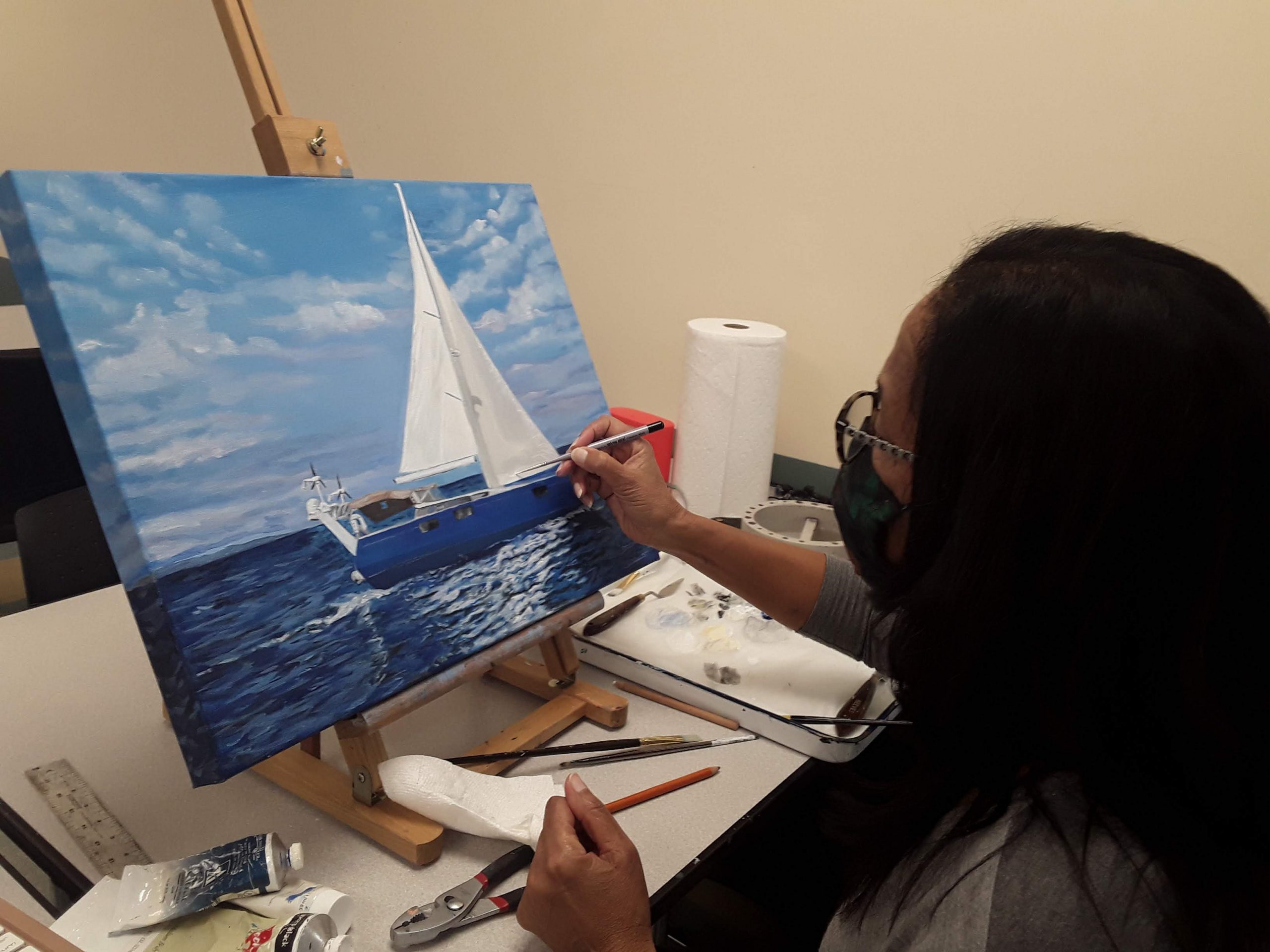 Student painting a sailboat on an easel