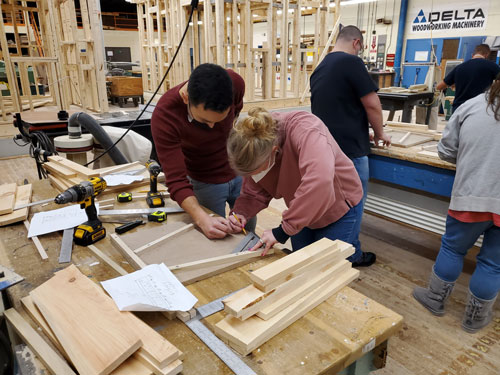 In Basic Carpentry, two students mark cutting their wood