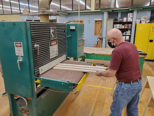 In Millwork, a student places more wood to cut