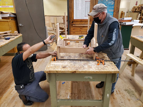 In Millwork, two student make a crate together by using a c-clamp