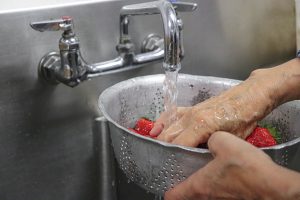 person washing strawberries in a sink